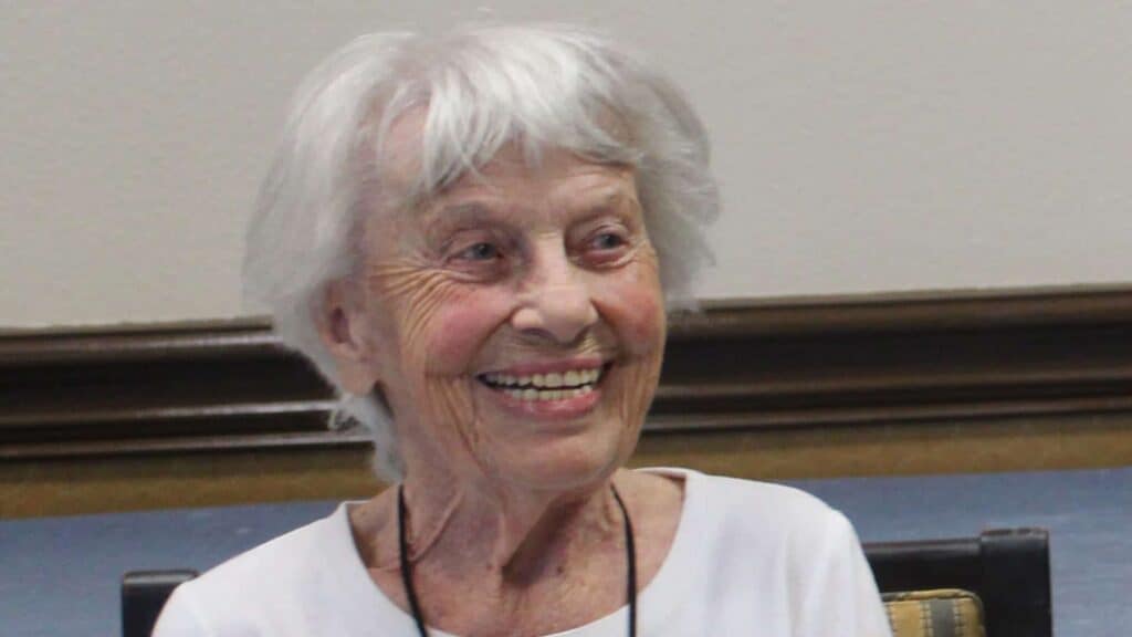 Smiling elderly woman with white hair indoors.