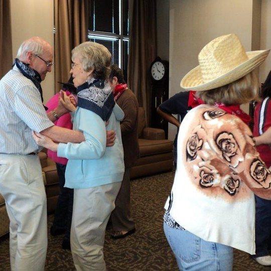 Group dancing indoors, wearing bandanas and hats.